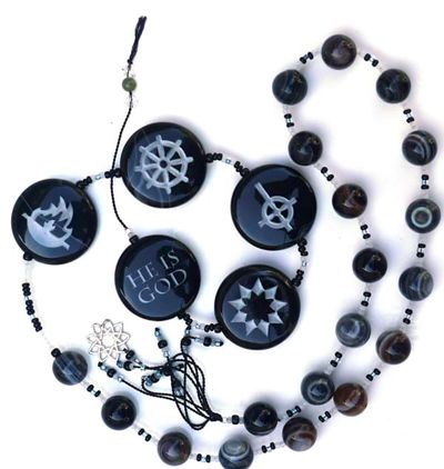 A set of prayer beads: black onyx with various religious symbols, and the lead bead engraved with "He is God".