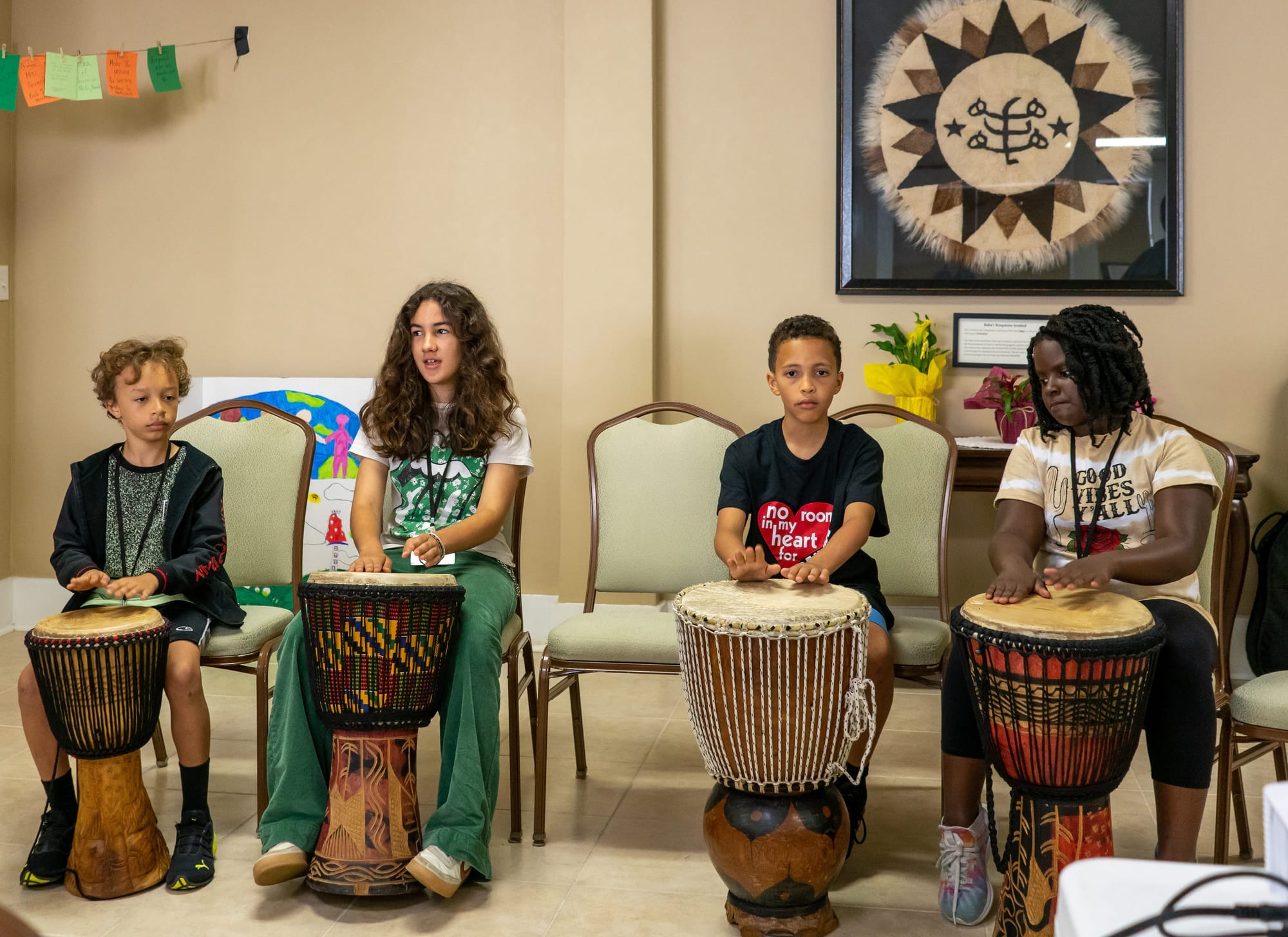 Four junior youth on stage drumming on Jembes, at the Savannah Georgia conference in 2023