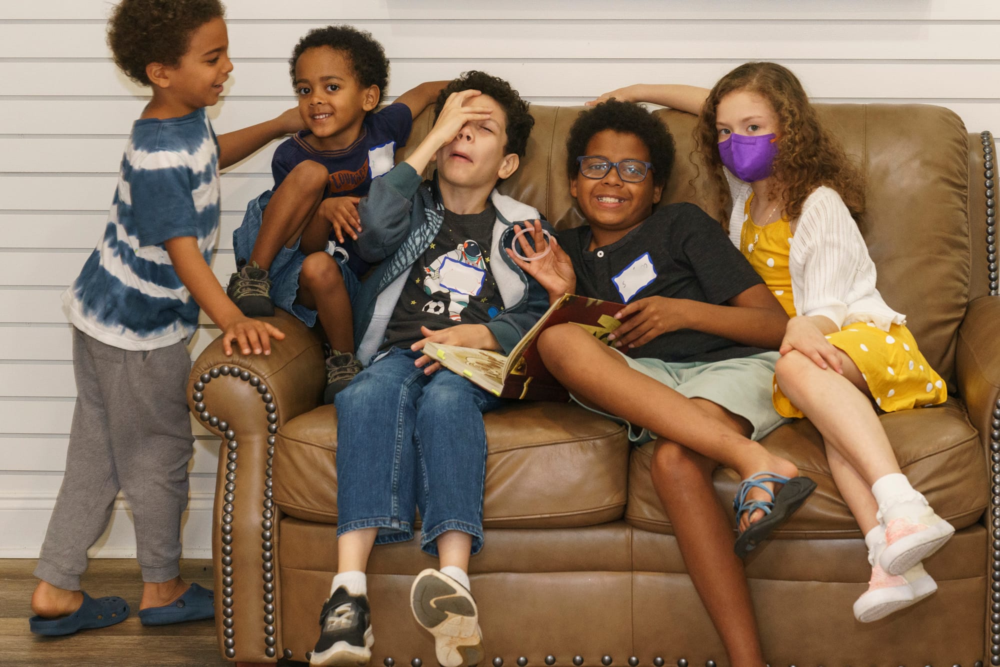 A few children casually pose on a sofa