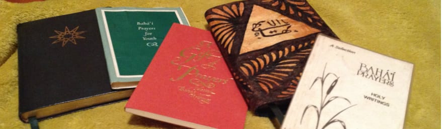 Several different Baha'i prayer books laying on a table.